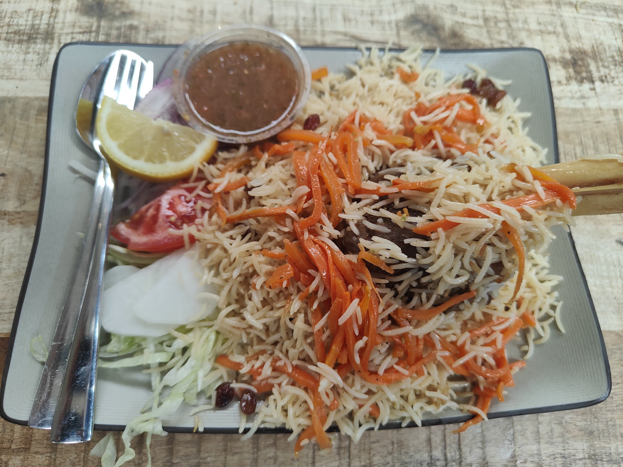 Rijst met wortel, rozijnen en salade op een vierkant bord
